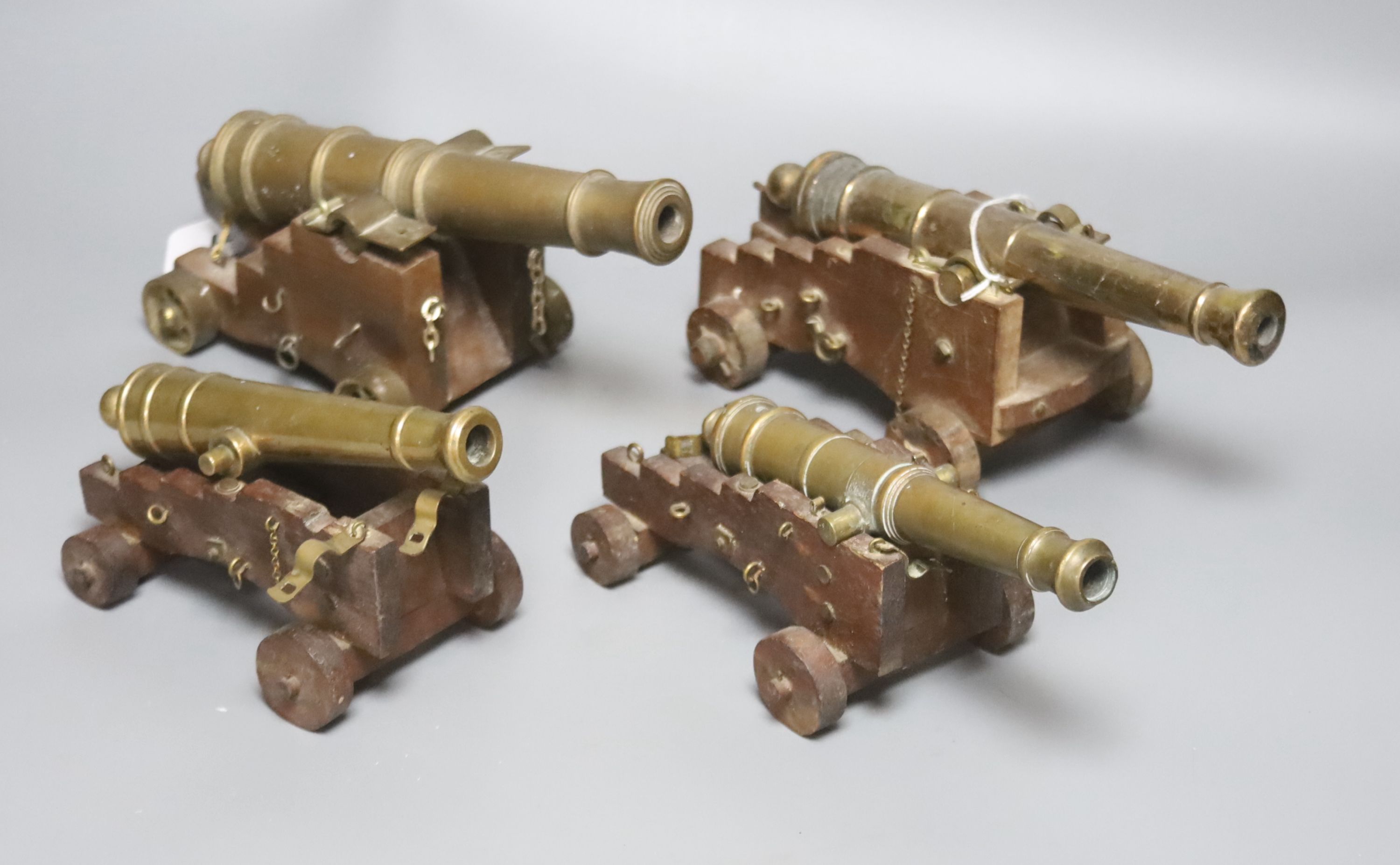 Four bronze or brass model cannons, with associated wood carriages, 20th century, barrel lengths 18-24.5cm